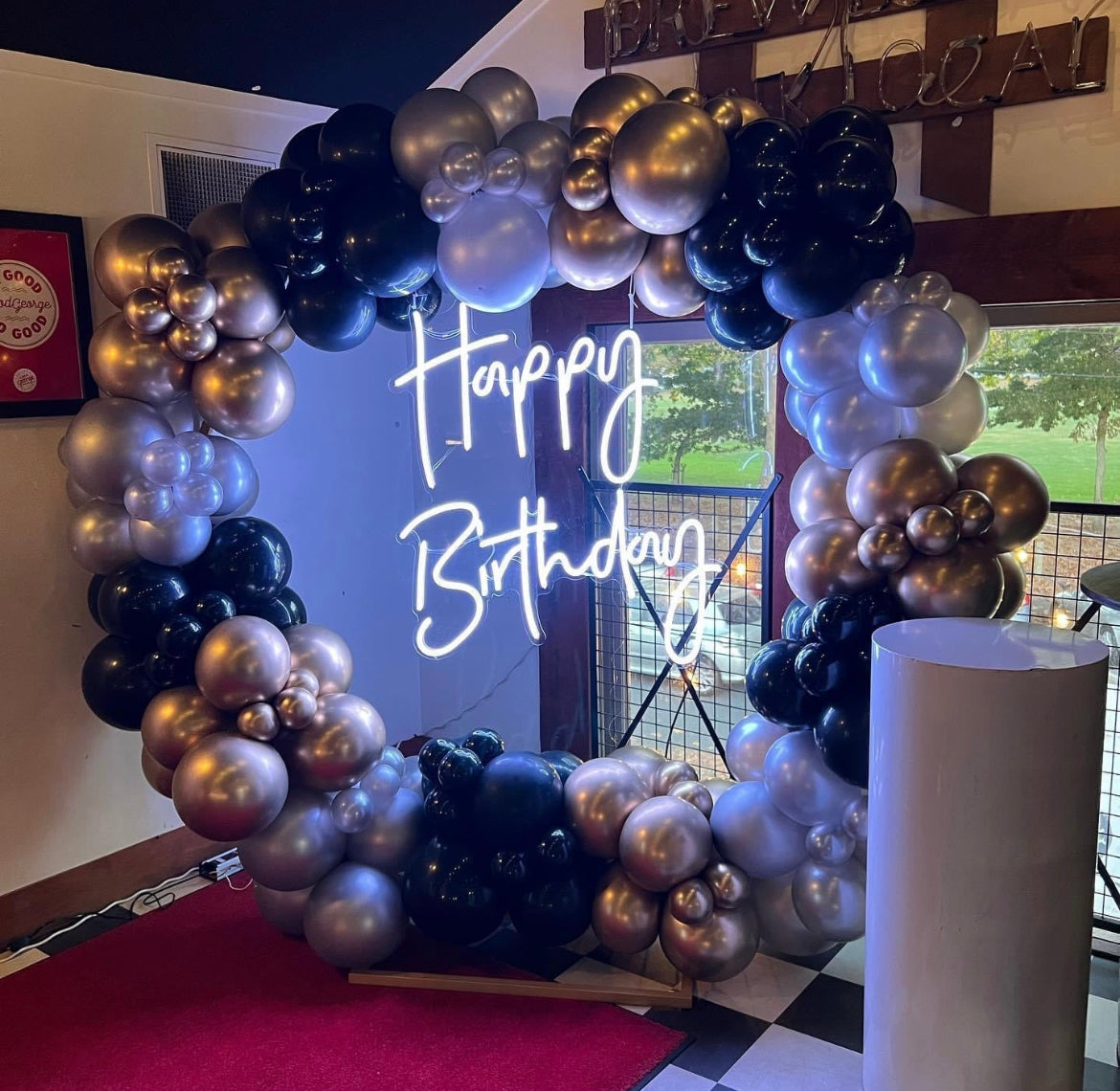 Balloon garland on round ring backdrop with happy birthday neon and cake stand event decorations for hire for birthday event 